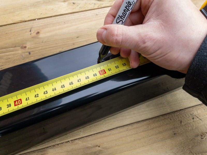 Measuring the guttering to length using a tape measure and marker.