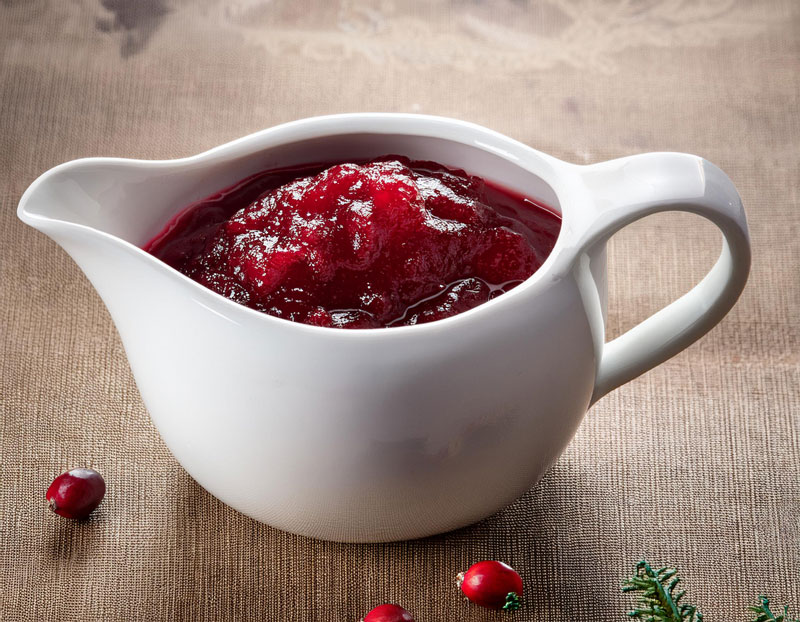 A small white jug of cranberry sauce sat on a table